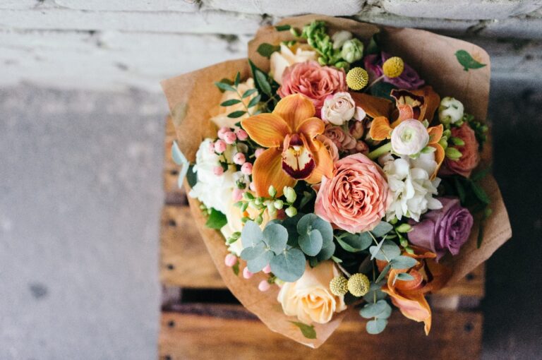 Bunter Strauß aus verschiedenen frischen Blumen vor einer Ziegelwand.