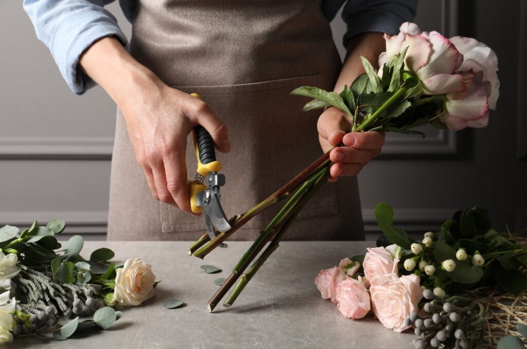 Florist, der am Arbeitsplatz mit einer Gartenschere Stiele von Schnittblumen abschneidet
